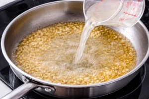adding pasta water to make creamy alfredo sauce