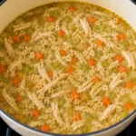 Freshly cooked Mendocino Farms lemon chicken soup ready to serve in a large pot with chicken and vegetables